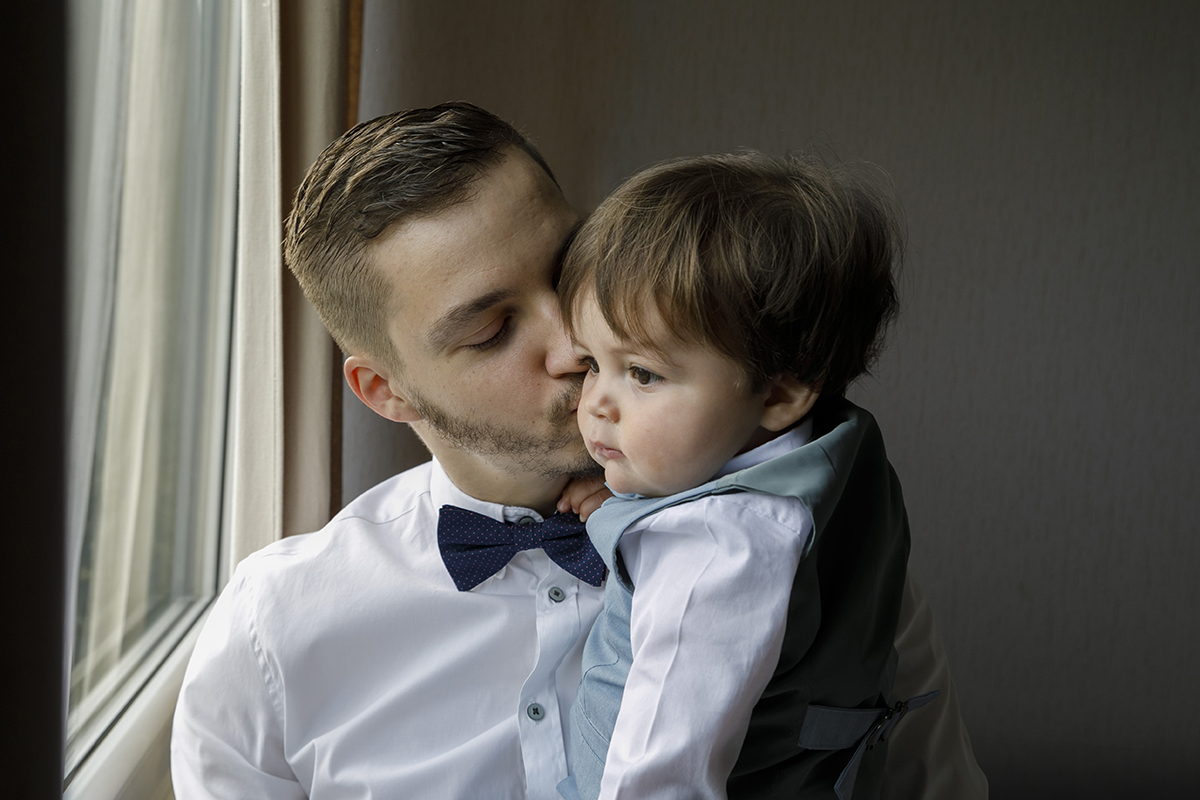 Num plano mais fechado, o pai beija a bochecha do filho com ternura. Gabriel mantém o olhar distante, contemplativo. A imagem respira amor e cumplicidade.