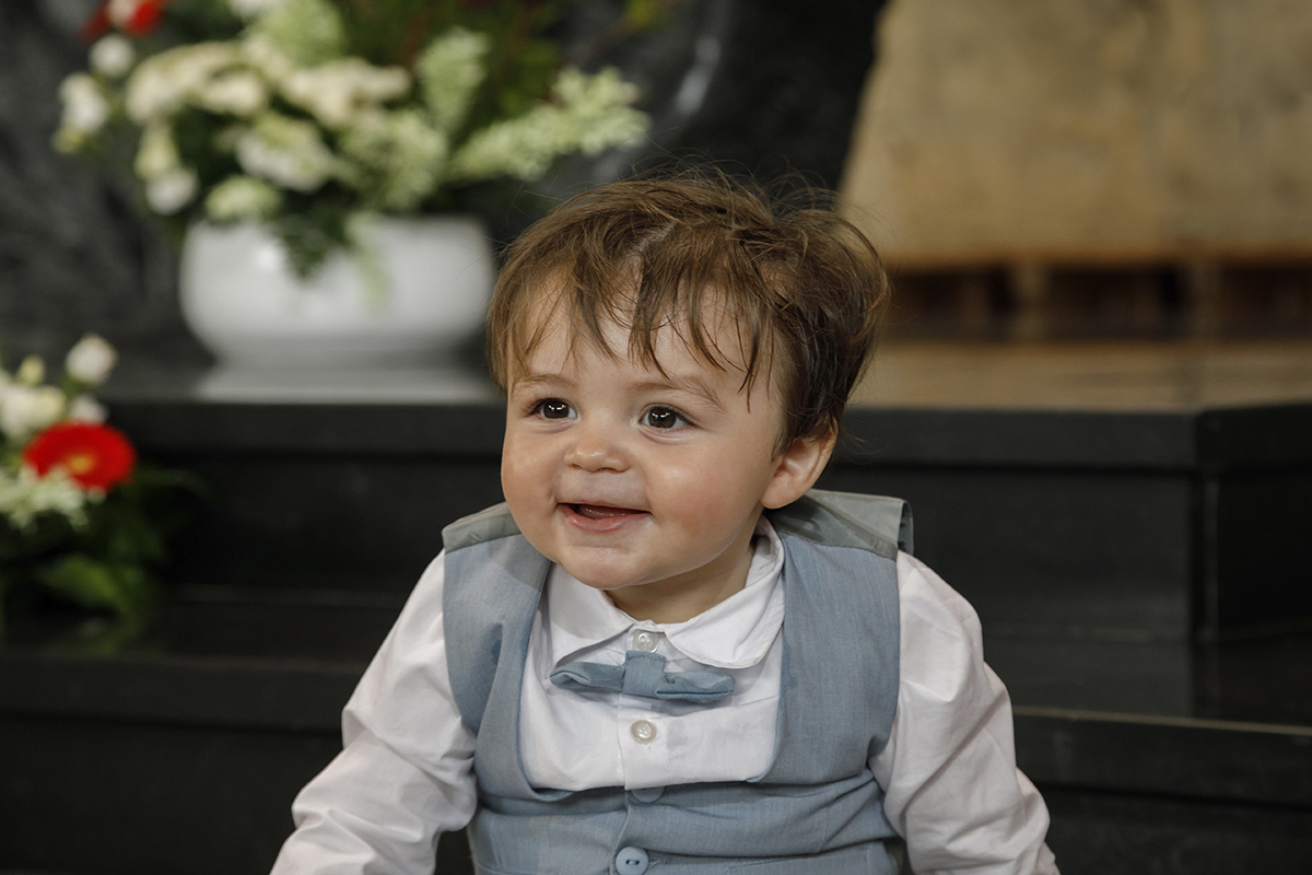 Sentado numa escada escura, Gabriel sorri ligeiramente para o lado. A luz desenha-lhe o rosto num plano mais próximo, onde o fundo desfocado realça a sua expressão feliz.