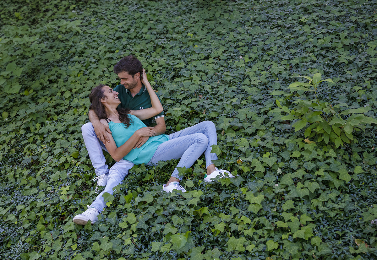 Diana deita-se com a cabeça apoiada na perna de André, que a recebe com carinho. Um olhar apaixonado une-os enquanto a natureza os envolve.