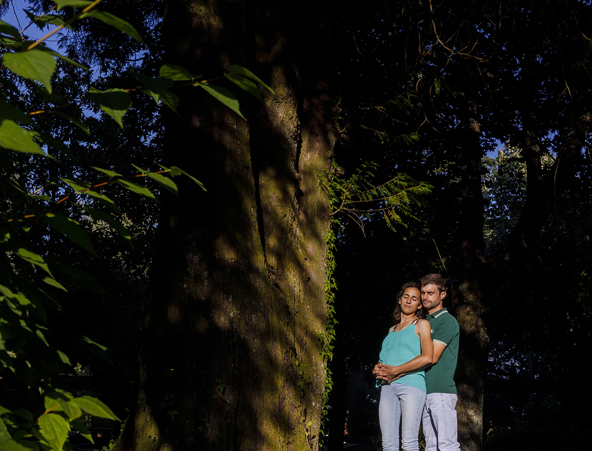 Abraçados com delicadeza, envoltos por luz dourada, Diana e André partilham um momento de paz e carinho entre troncos e folhagem.