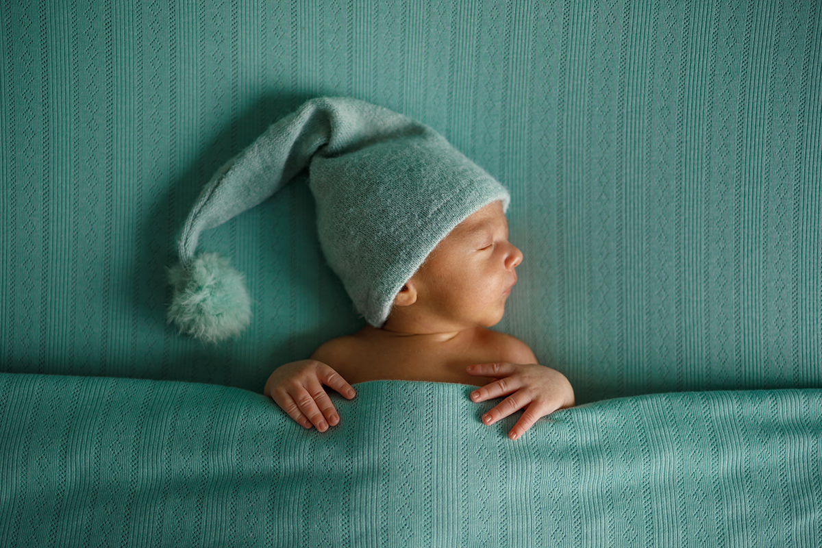 Tapado com o mesmo lençol verde, Daniel surge agora de frente, com a cabeça virada de perfil. O seu gorro e a pose tranquila criam uma fotografia de puro carinho e suavidade.