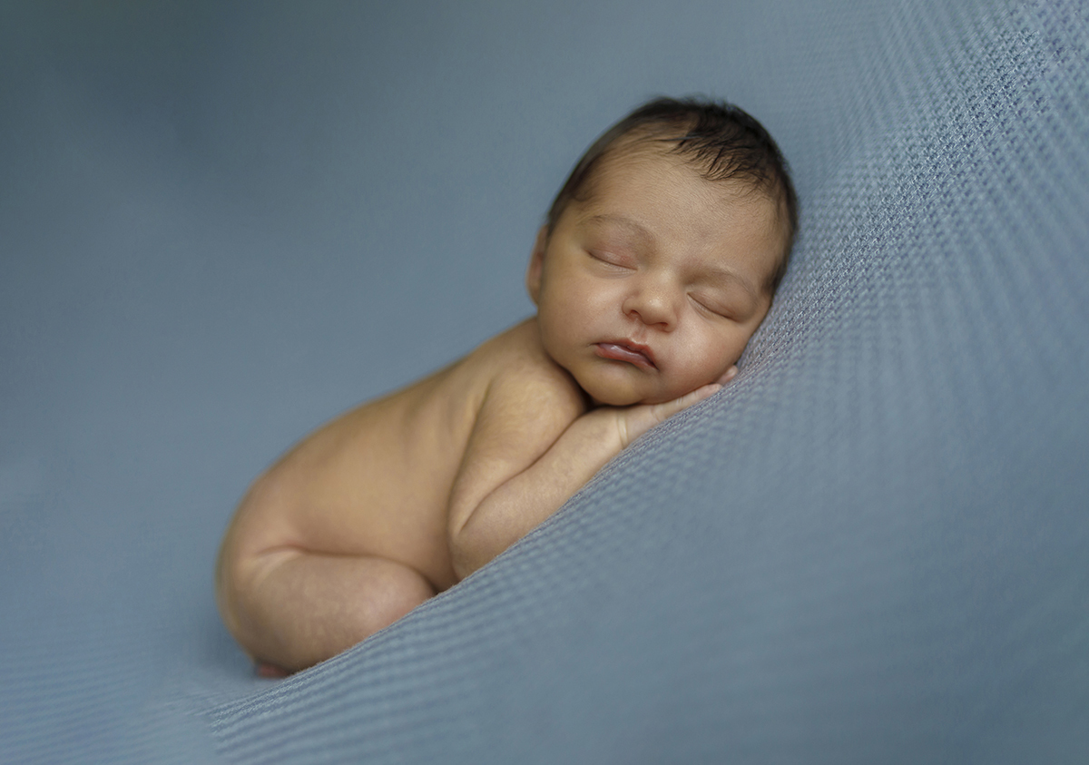 Enrolado num tecido azul bebé, Daniel dorme de costas, moldado pela manta que o envolve. As mãos debaixo da carinha fazem-nos imaginar o calor de um abraço invisível.