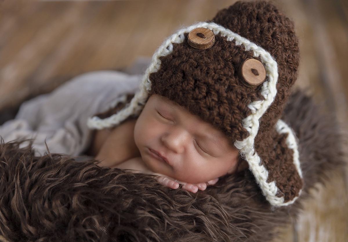 Num retrato aproximado, o rosto de Daniel é o centro da imagem. Com um gorro castanho e branco de botões, ele dorme profundamente, num registo com fundo desfocado que emana calor humano.