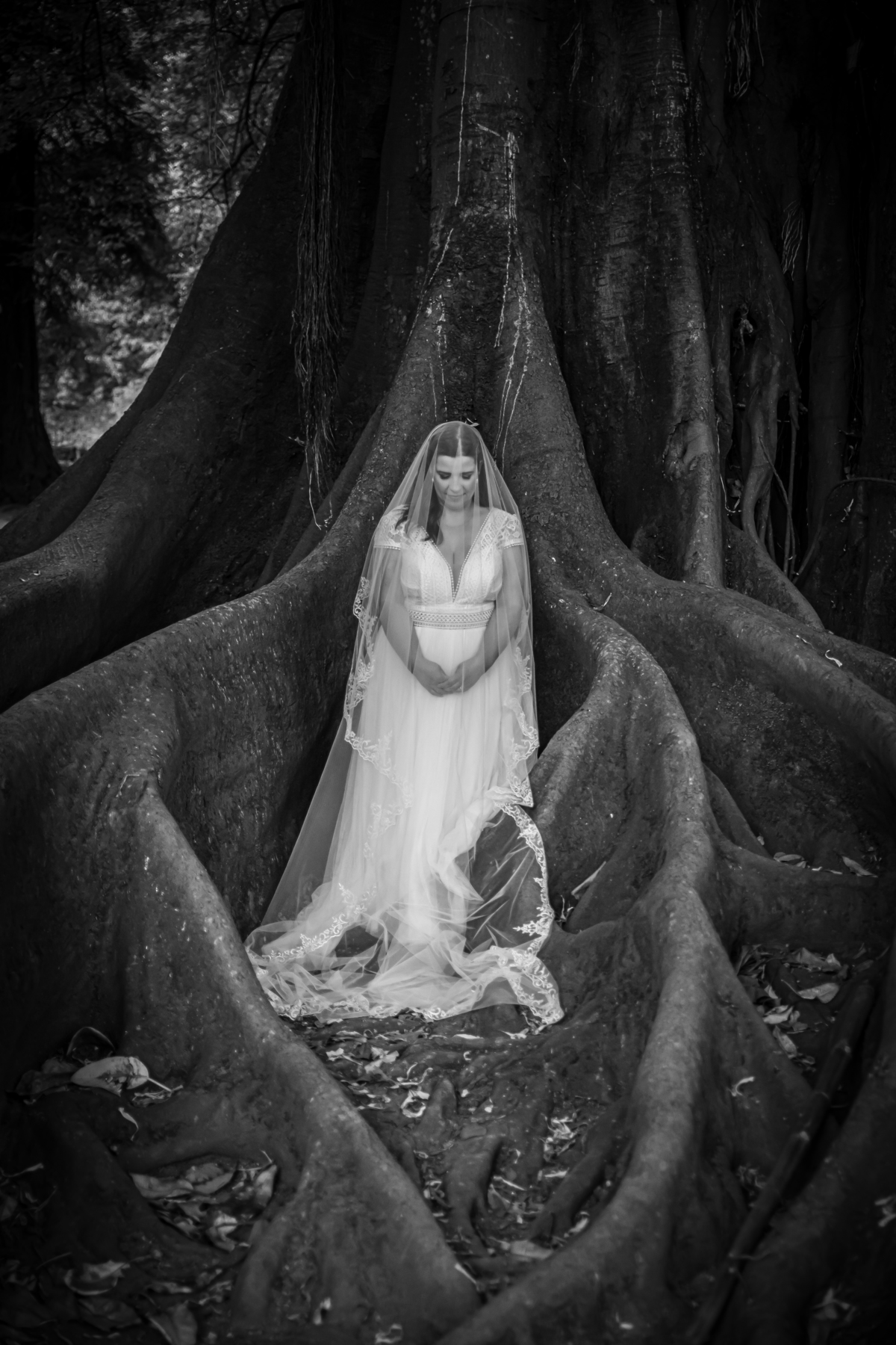 De corpo inteiro entre as raízes, Mónica está de mãos dadas e com o véu a cair em harmonia. A preto e branco, esta imagem completa a sequência de serenidade e beleza natural.