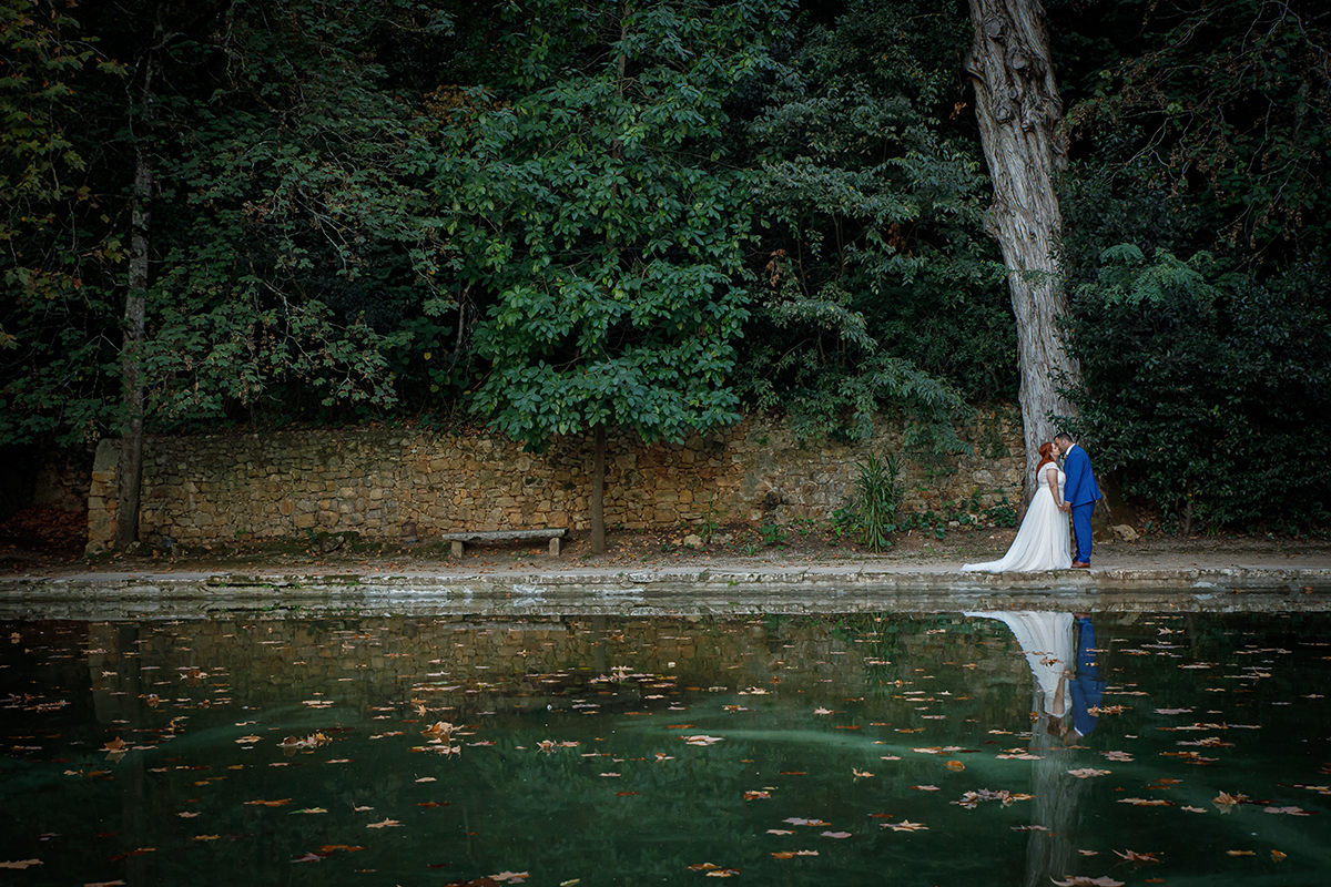 Junto ao tanque, de mãos dadas, os dois beijam-se com uma árvore por trás a enquadrar a cena. O reflexo na água multiplica o amor, espelhando-o como uma poesia visual.