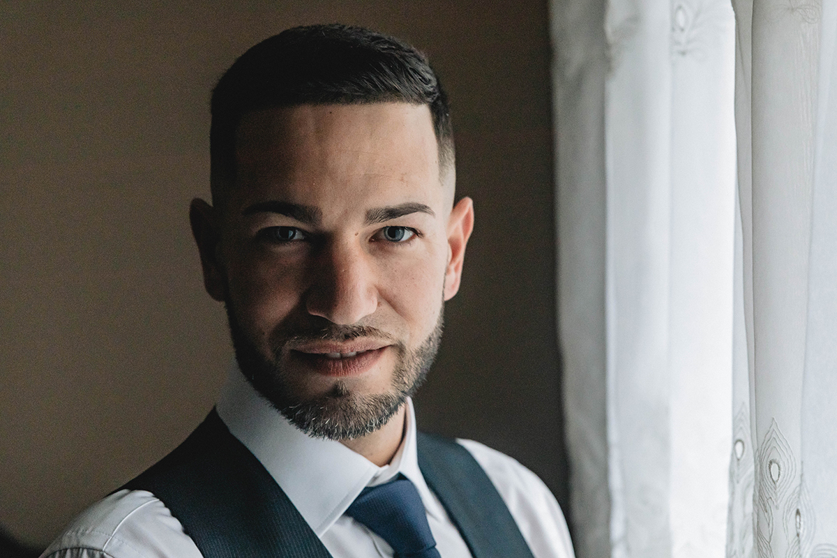 Com um olhar firme e coração leve, o noivo encara a objetiva, onde metade do seu rosto se ilumina com a promessa do dia.