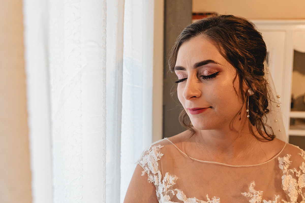 De olhos fechados e rosto sereno, ela sente o momento com um sorriso calmo, rodeada pela luz que entra pela janela.