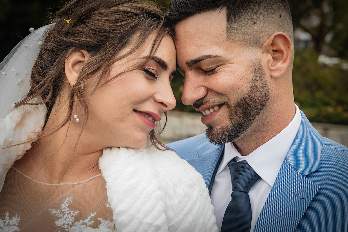 Frente a frente, os noivos tocam-se com ternura. Olhos fechados, rostos colados, partilham um instante de amor e cumplicidade.