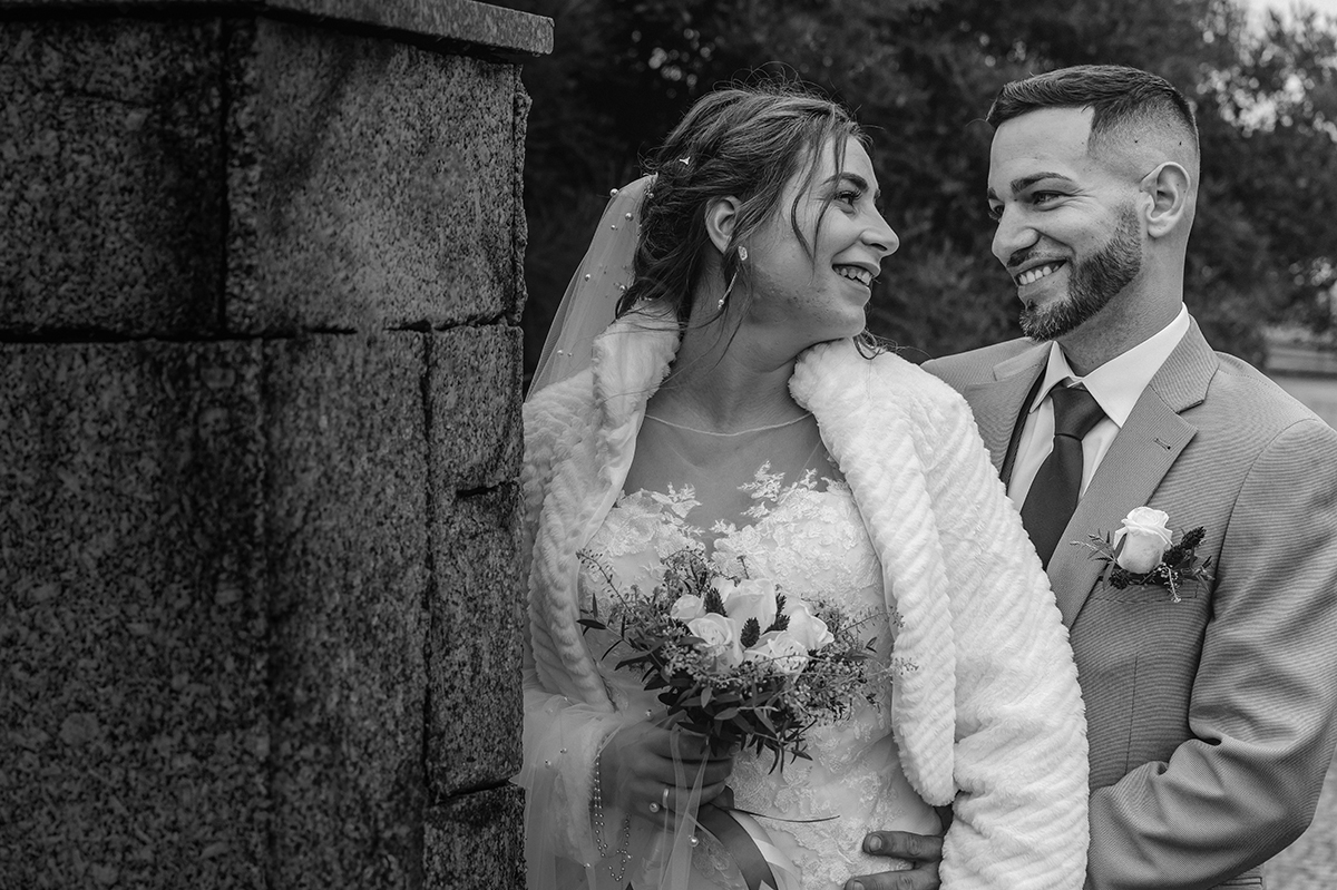 Entre pedras e promessas, César olha Sandra com amor, enquanto ela, de costas, devolve-lhe o olhar com um bouquet ao peito, ambos certos da escolha.