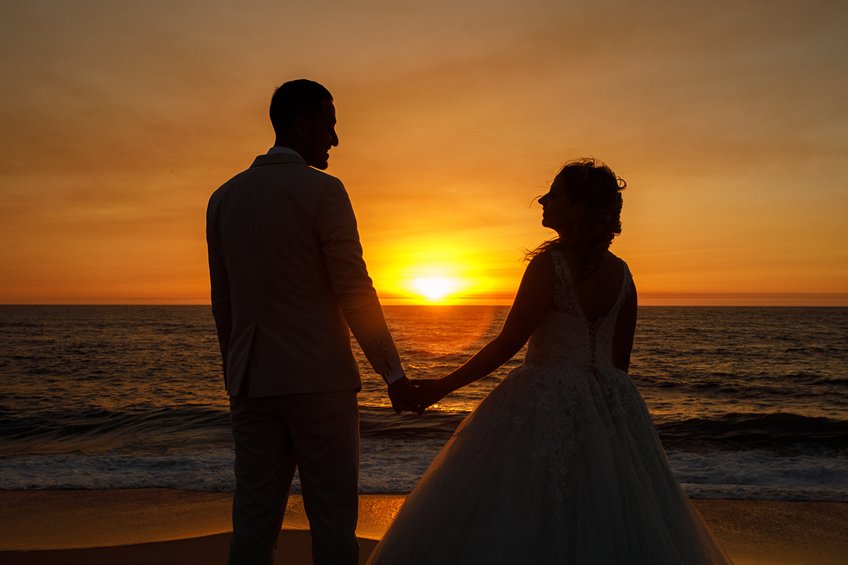 Num plano mais fechado, vemos os noivos dos joelhos para cima, de mãos dadas, virados um para o outro. O sol espreita entre eles, criando um efeito visual impressionante.