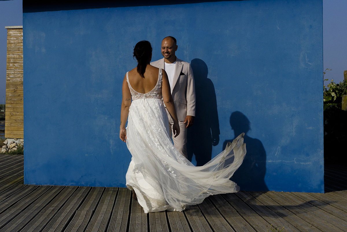 Bruno está muito próximo da parede azul a sorrir para Patrícia, que está à sua frente. O vestido dela voa e as suas sombras refletem-se na parede, criando uma imagem mágica.