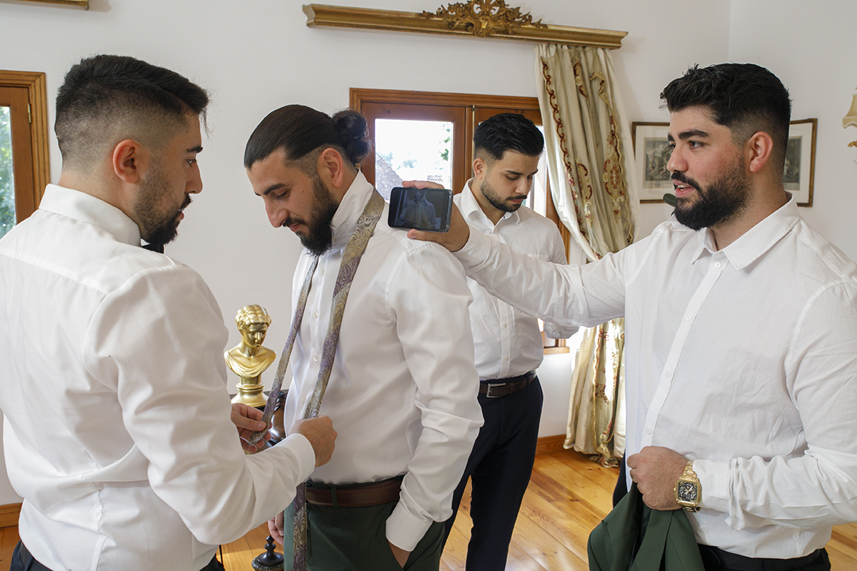 Ainda no quarto, Furkan sorri enquanto olha para baixo, rodeado pelos padrinhos.