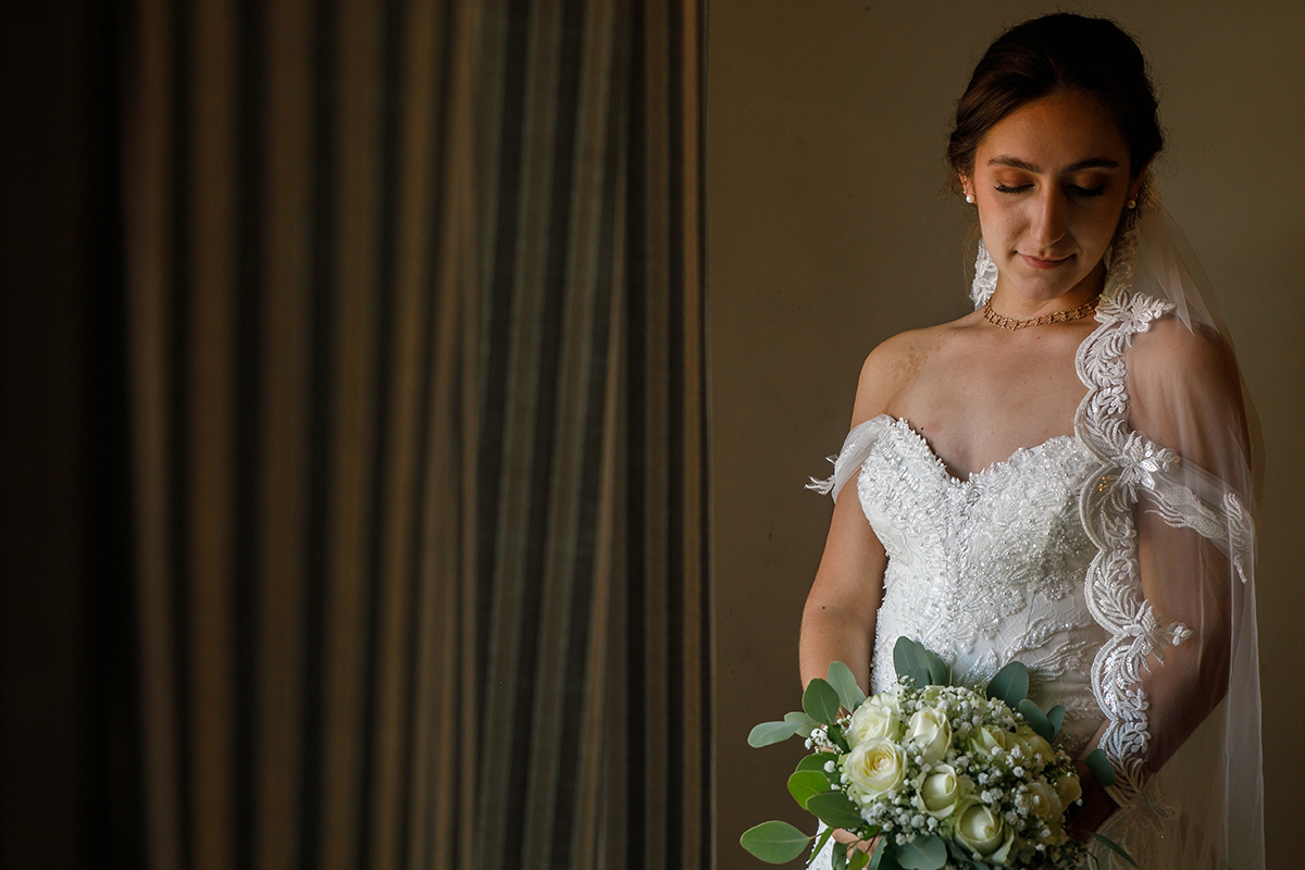 Num fundo de cortina e parede, Carolina contempla o bouquet, num registo delicado.