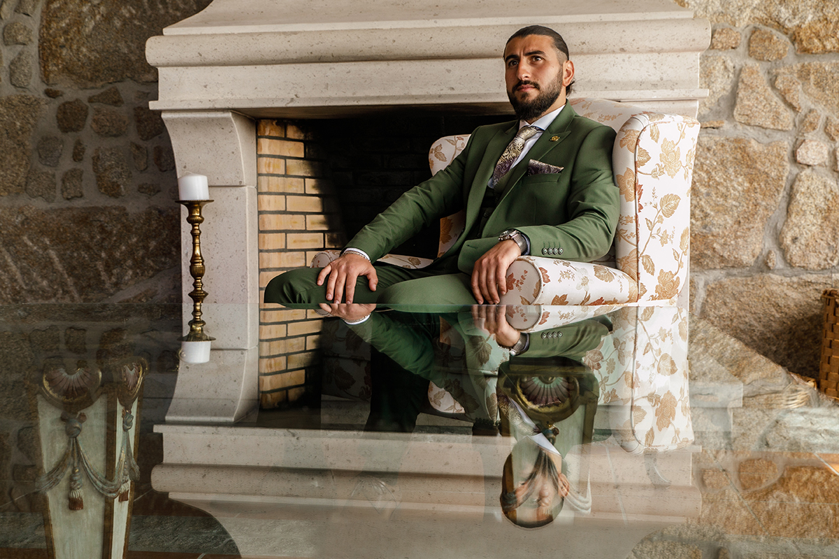 Sentado junto à lareira, pensativo, com um ambiente acolhedor.