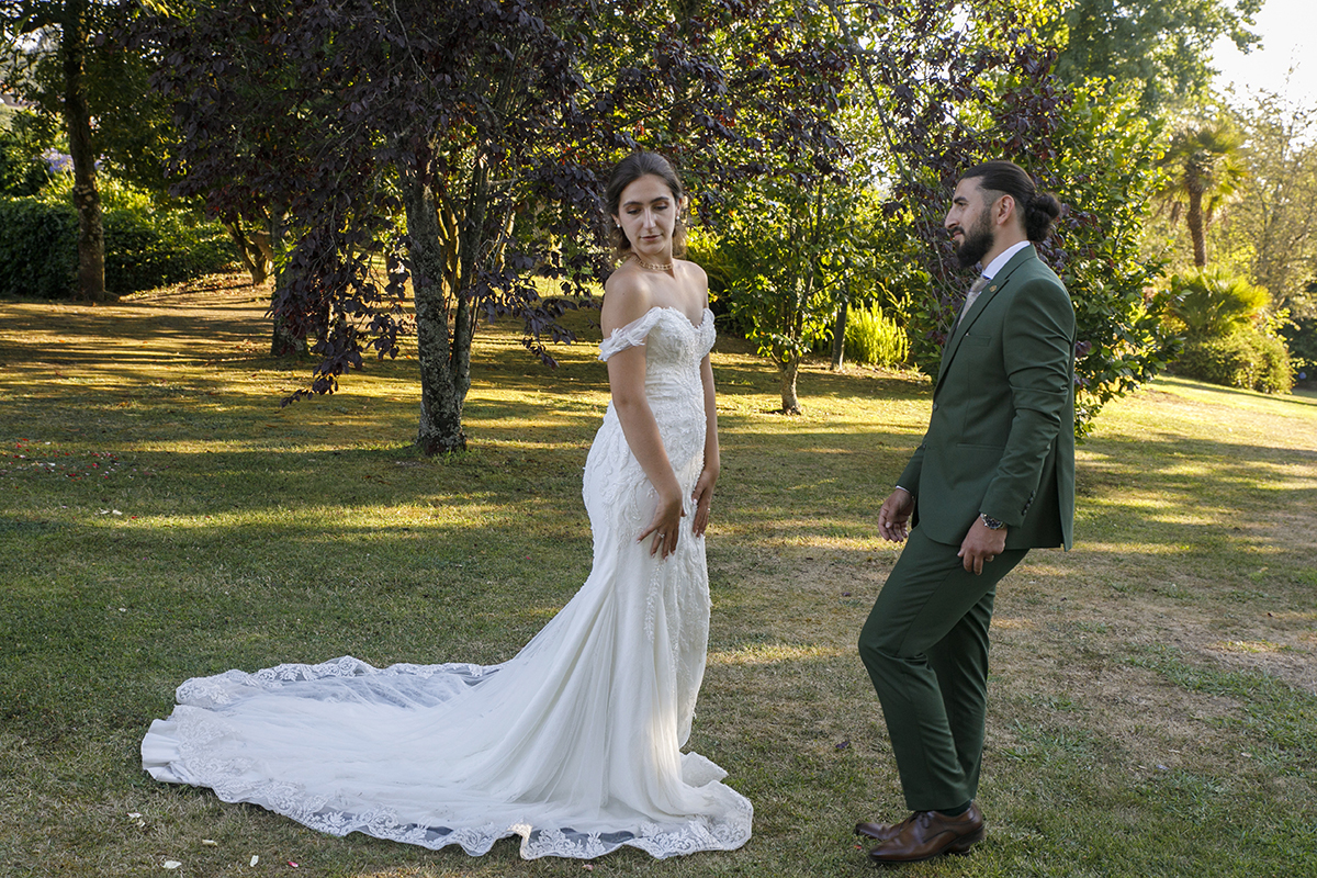 Em cenário verdejante, Furkan olha para Carolina, ela sorri discretamente.