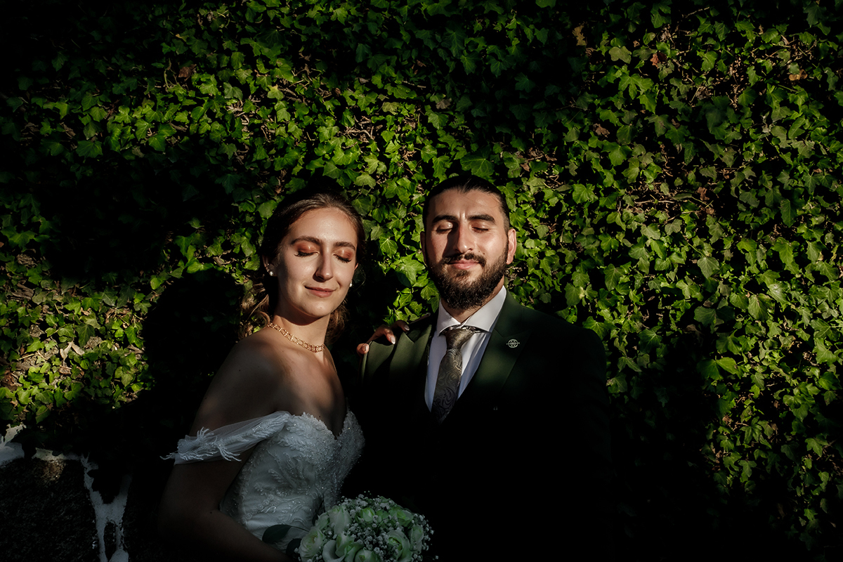 Encostados numa parede de trepadeiras, olhos fechados, banhados pela luz do sol.