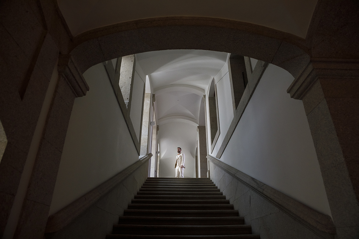 Nas escadas históricas da Pousada de Viseu, Mathieu olha cá para baixo com serenidade. A claridade envolve-o e o cenário ganha vida, como se o espaço reconhecesse a importância daquele dia.