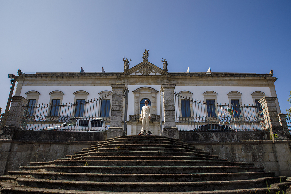 À entrada da imponente Pousada de Viseu, com a escadaria e o portão abertos, Mathieu olha confiante para a câmara. Uma imagem que exala presença, força e paz num dia inesquecível.