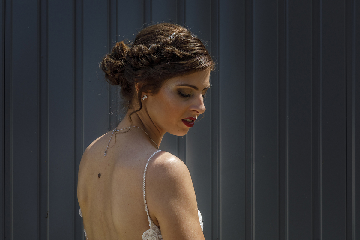 Um plano mais aproximado onde Marta está ligeiramente de costas e olha para baixo, reflexiva. A parede escura ao fundo intensifica a tranquilidade e profundidade do momento.