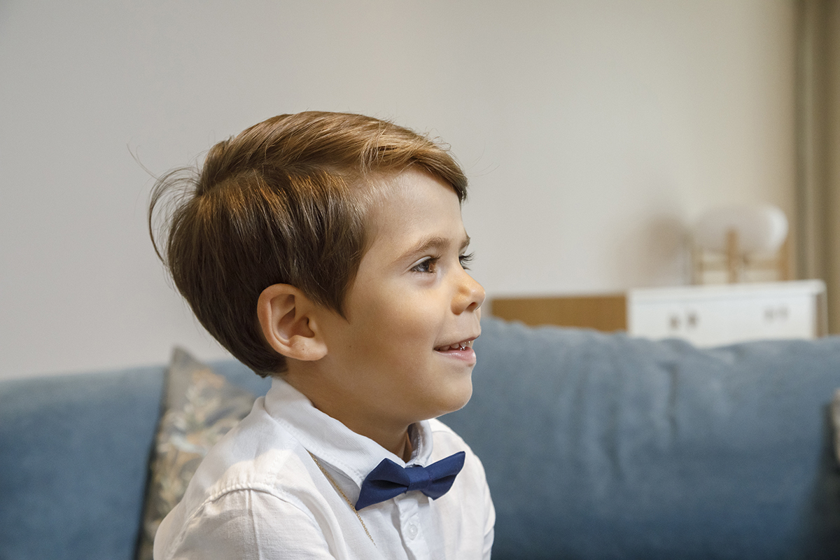 Ethan surge num retrato encantador, captado do peito para cima. Está de perfil, com um sorriso sereno no rosto, a olhar confiante para o futuro, enquanto o fundo desfocado dá todo o destaque à sua expressão luminosa.