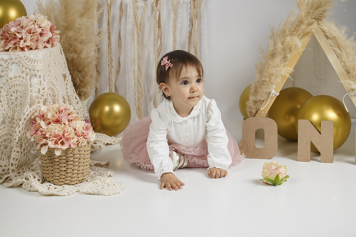 Num cenário repleto de detalhes encantadores como rosas, balões dourados e letras 