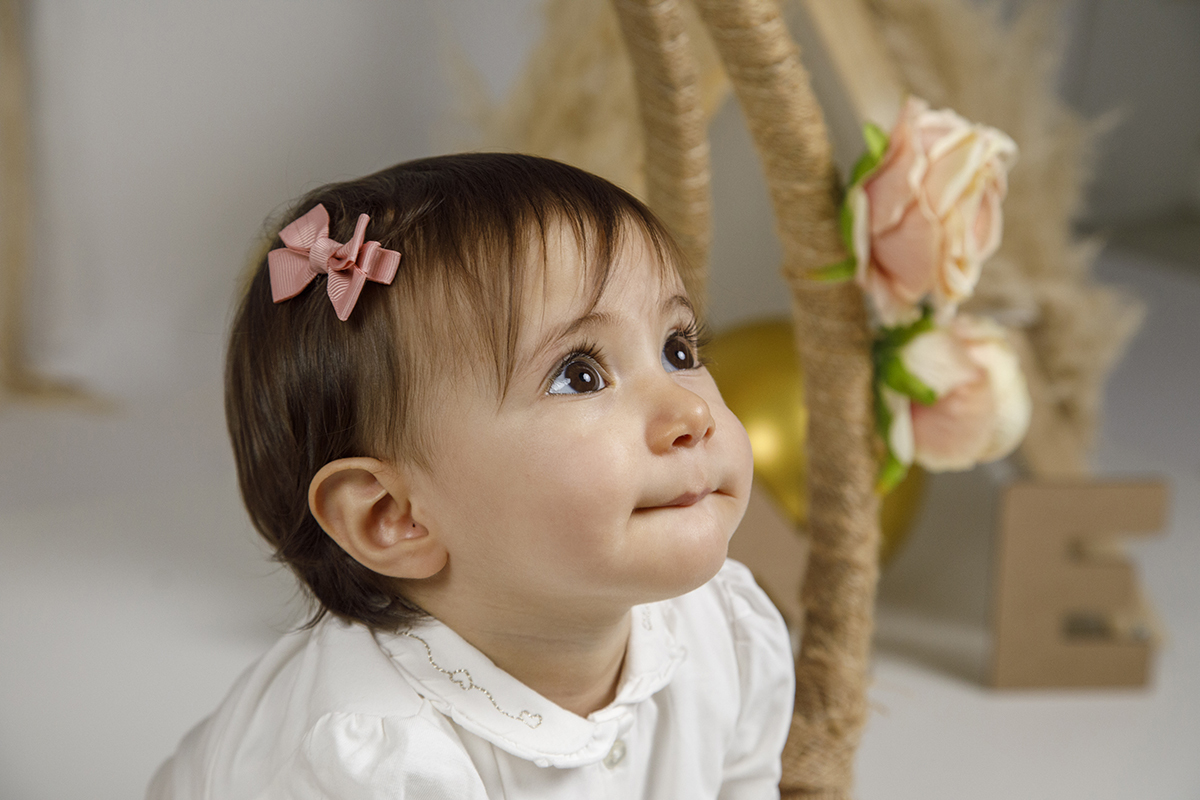 Num plano mais fechado dos ombros para cima, Matilde olha para cima com ar concentrado e um leve mordiscar do lábio. Em destaque, também vemos algumas das rosinhas delicadas do banquinho.