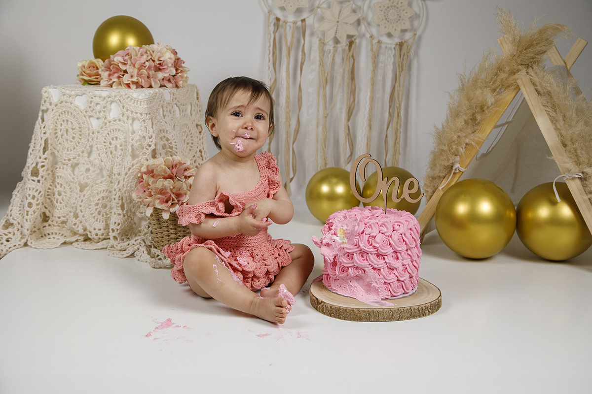 A olhar para cima e com a boca cheia de bolo cor-de-rosa, Matilde está rodeada por migalhas. A sua expressão divertida mostra o quanto está a desfrutar do momento doce e caótico do Smash the Cake.