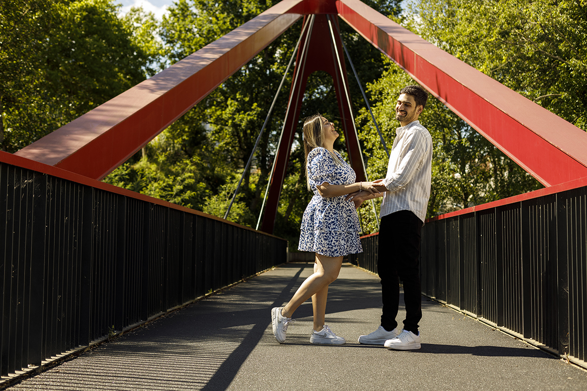 e mãos dadas, inclinam as cabeças para trás a rir com vontade, um momento de pura diversão.