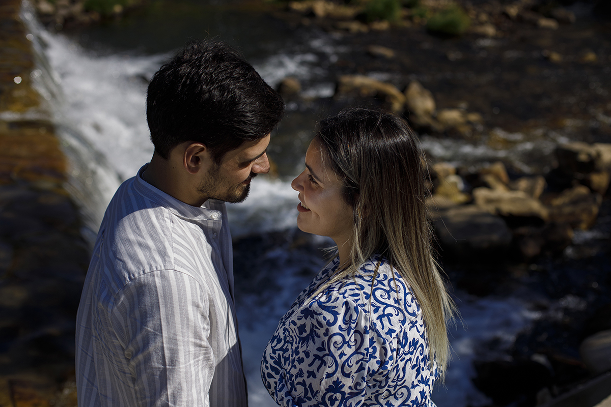 Frente a frente, com sorrisos sinceros, num cenário natural onde corre uma cascata. O olhar entre eles diz tudo.