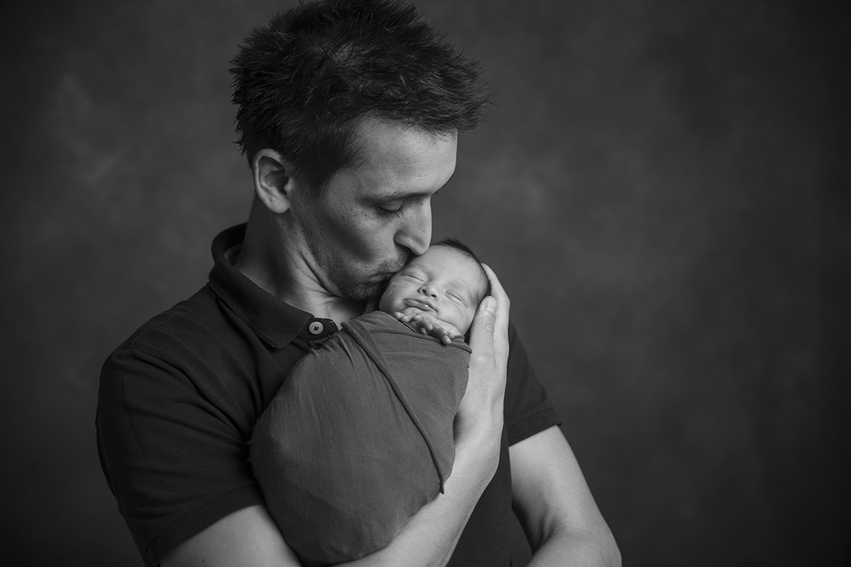 Em preto e branco, o pai segura o pequeno Gabriel ao colo e beija-lhe carinhosamente a testa.