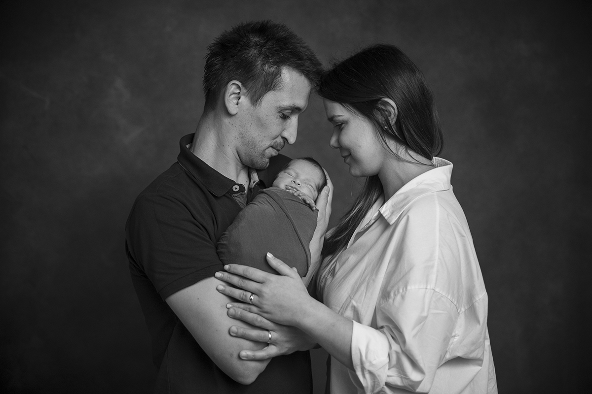 A preto e branco, vemos os pais de perfil com Gabriel no meio, os dois olham carinhosamente para o filho.