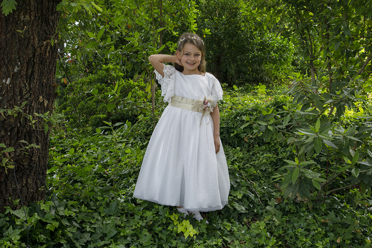 Rodeada por trepadeiras verdes, Letícia coloca uma mão atrás da cabeça e sorri, irradiando felicidade.