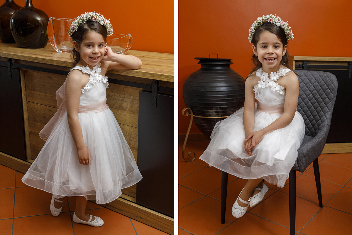 Junto a um móvel de madeira, Joana encosta-se com naturalidade. Um dos braços repousa sobre o móvel e a mão toca o rosto num gesto espontâneo. Noutra foto, está sentada numa cadeira cinza, com os pés cruzados e as mãos sobre as pernas, muito bem-disposta.