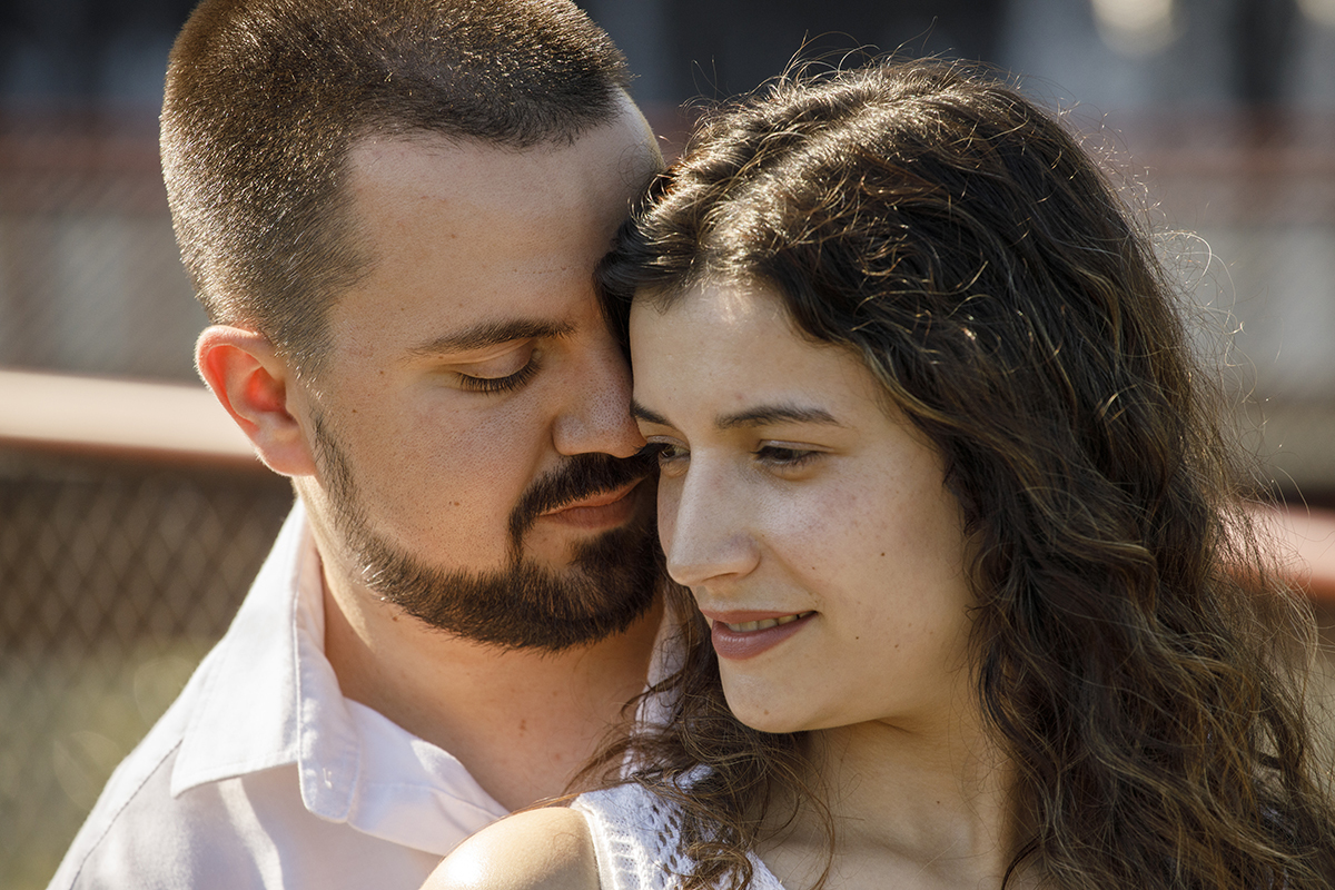 Sandra sorri levemente, abraçada por Rafael, num momento íntimo e sereno de puro afeto.