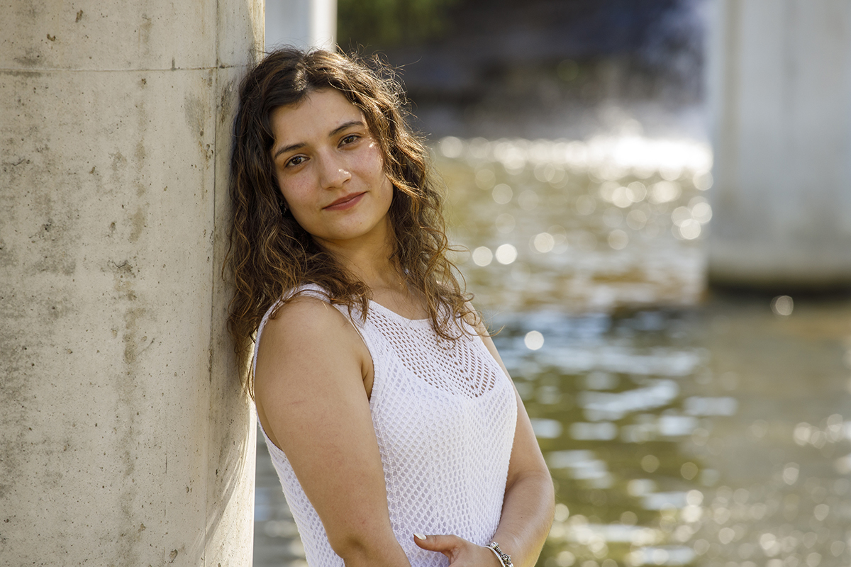 Plano aproximado de Sandra, serena, rodeada pelos pilares e pela natureza.