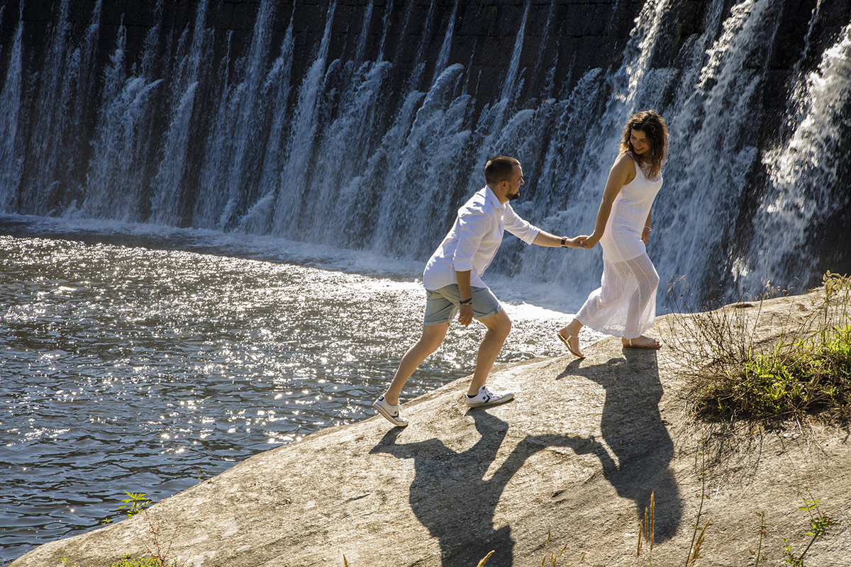 De mãos dadas, sobem a rocha junto ao rio, sorrindo um para o outro. Sessao solteiros Tondela Viseu