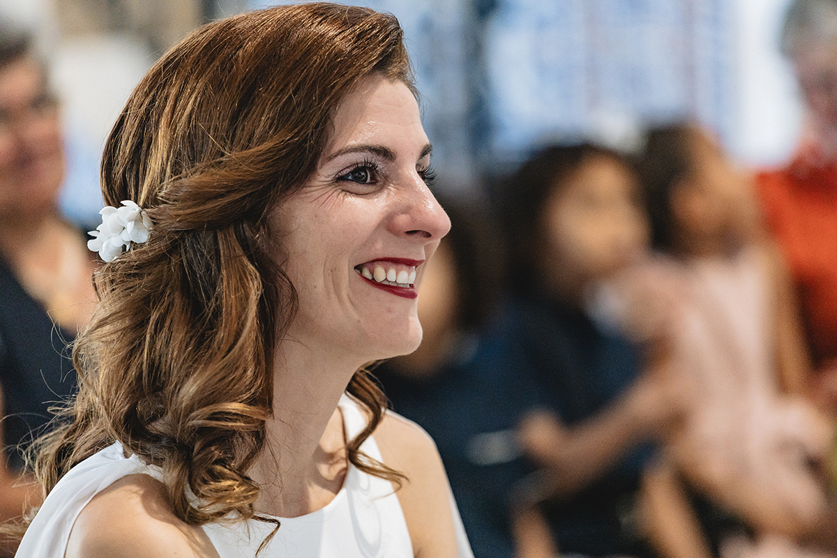 Com o véu delicadamente pousado, Ju observa o momento com um sorriso sereno. Um registo captado durante a cerimónia, cheio de significado.