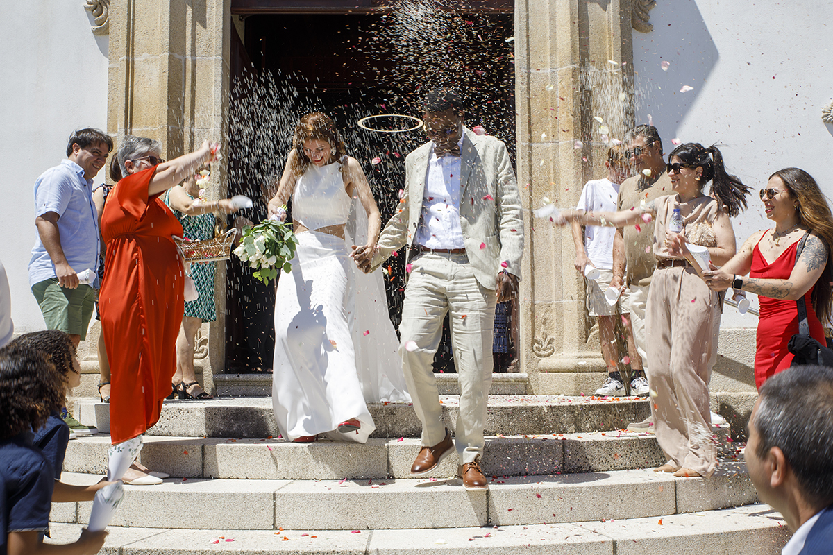 À saída da igreja, o arroz voa no ar como símbolo de prosperidade. Os noivos sorriem, rodeados pelo entusiasmo dos convidados. Foto Coimbra tondela