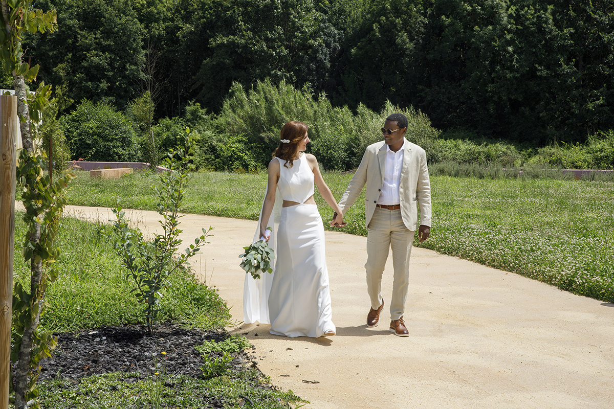 Mãos dadas, caminham sobre um trilho cercado de natureza. Os olhares trocados entre os dois dizem mais do que mil palavras.