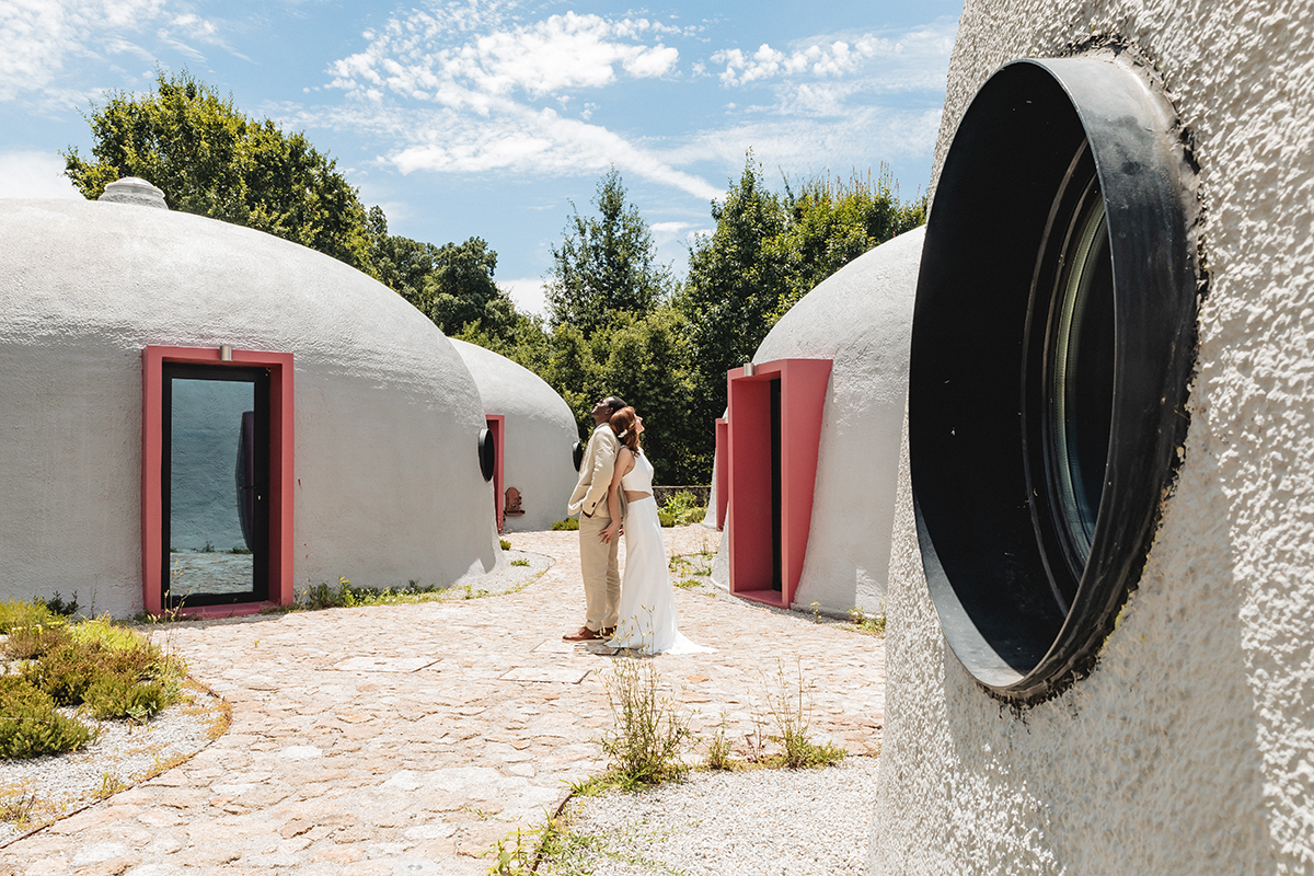 Composição em “S” criada pelas casas redondas e o caminho central. O casal aparece de costas um para o outro, cada um a olhar para o céu, num momento de contemplação a dois.