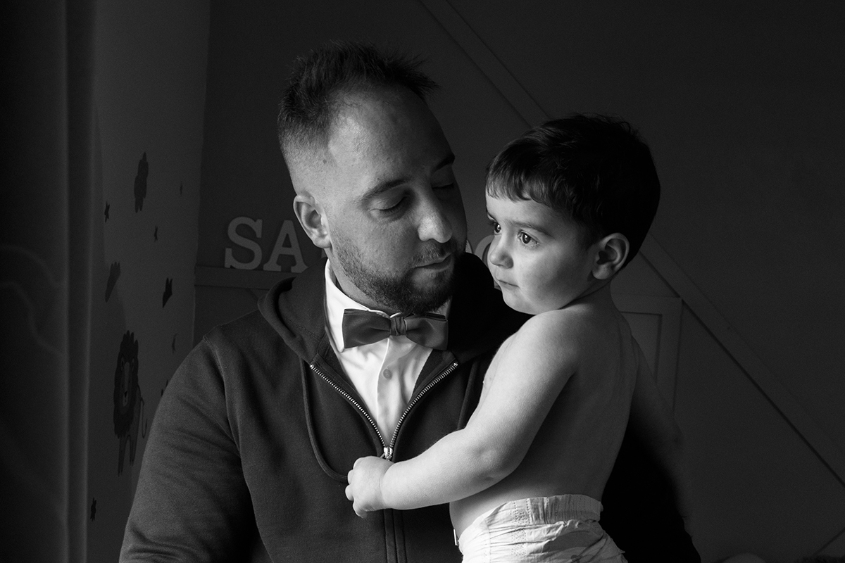 O pai segura o filho com firmeza e amor. Enquanto Salvador olha pela janela com um ar misterioso, o pai contempla-o com serenidade.