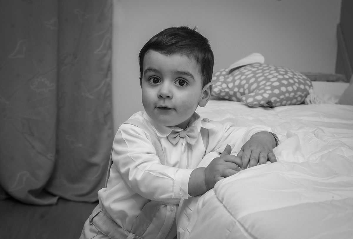 Sentado na cama, Salvador mexe nas mãos com curiosidade, como quem reflete sobre o mundo à sua volta.