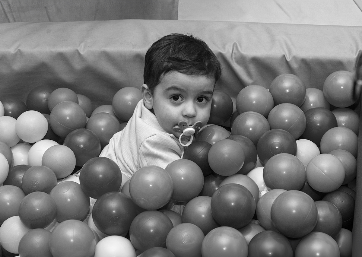 A preto e branco, Salvador repousa numa piscina de bolas, com a chupeta na boca e um ar tranquilo. Um instante de paz captado com doçura.