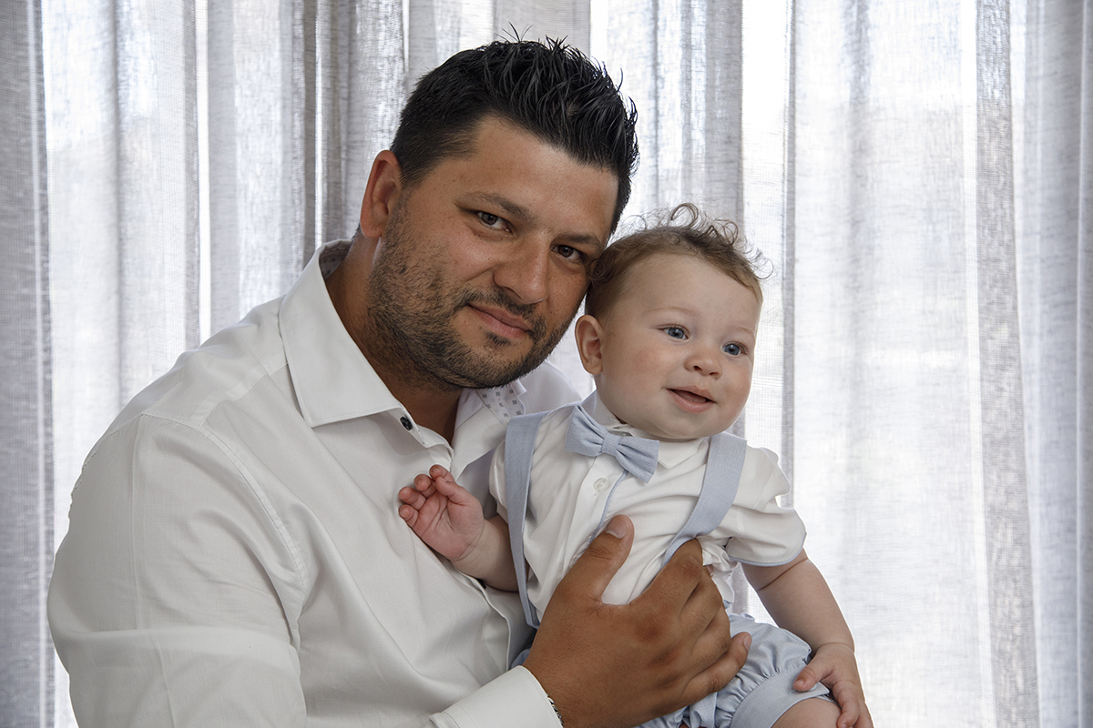 Nos braços do pai, Mário encosta o rosto ao dele, num instante cúmplice de sorrisos. O pai olha para a câmara, enquanto o pequeno observa algo à direita, ambos felizes.