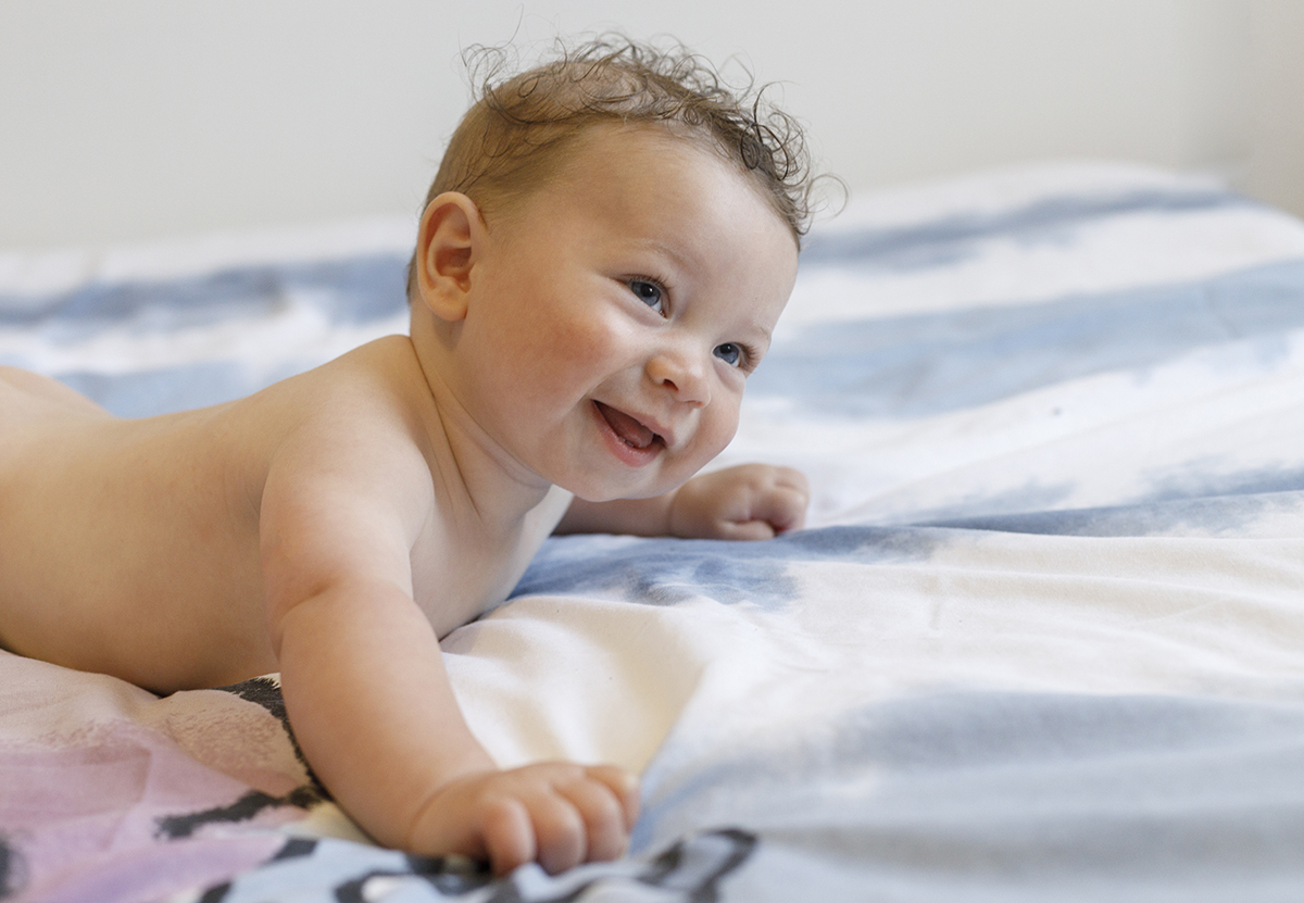 Deitado na cama, em tronco nu, Mário olha para o lado direito com um sorriso sereno.