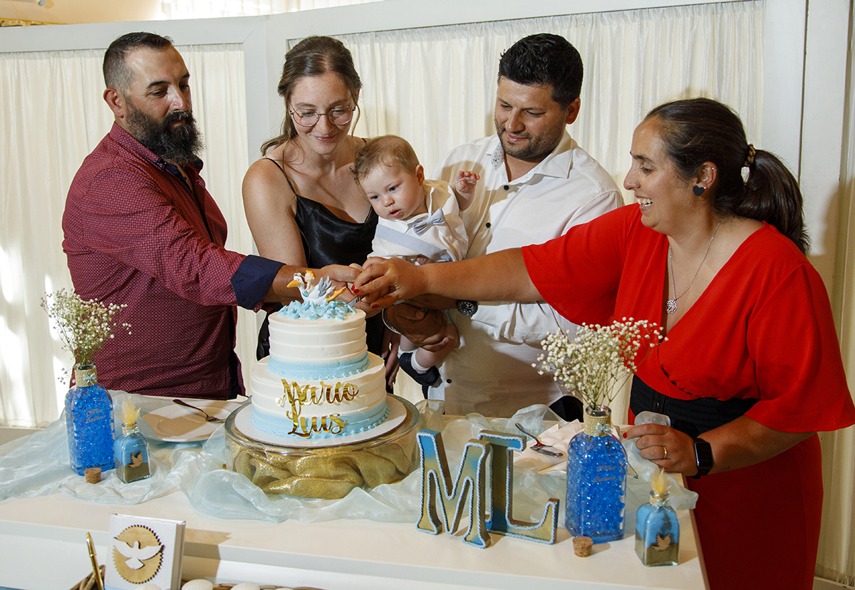 Com os olhos brilhantes, os padrinhos cortam a primeira fatia do bolo. Ao lado, os pais seguram o Mário com orgulho e partilham sorrisos de felicidade partilhada.