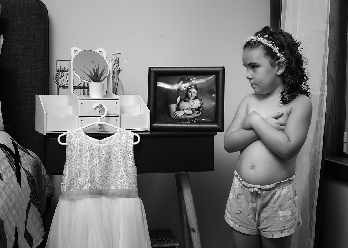 Iris observa, em silêncio, o seu vestido pendurado, com um olhar de expectativa.