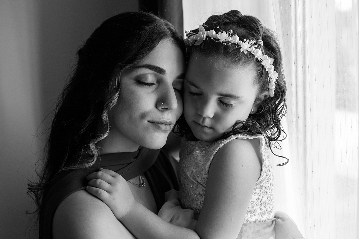 Num instante de paz, mãe e filha abraçam-se com os olhos fechados, numa fotografia a preto e branco que guarda a ternura do momento.
