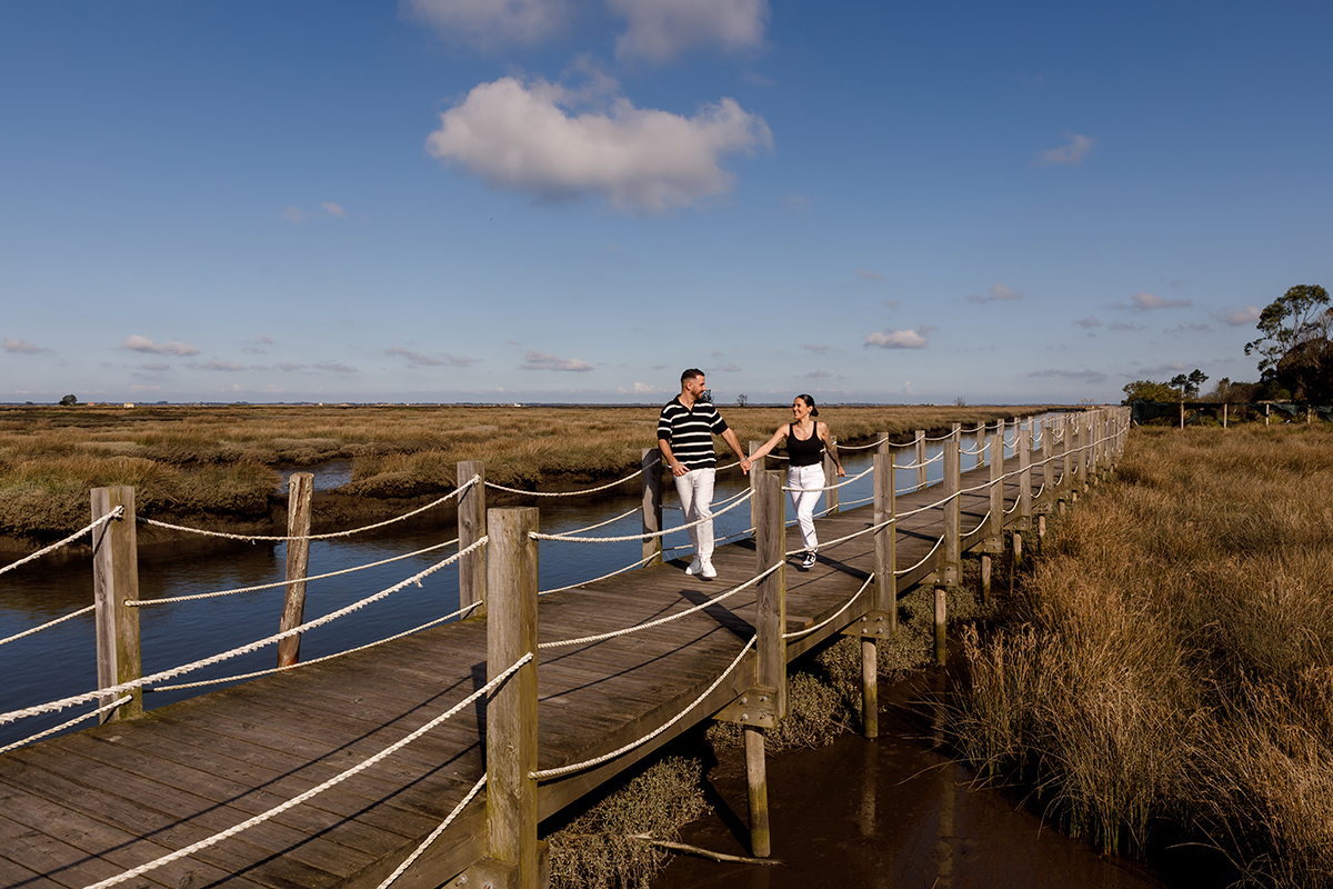Cumplicidade e sorrisos entre noivos nos passadiços de madeira em Aveiro.