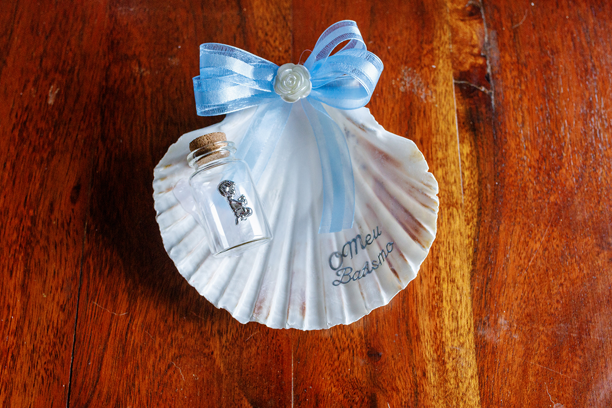 Close-up da concha batismal e da vela, símbolos da fé no batizado do Salvador.